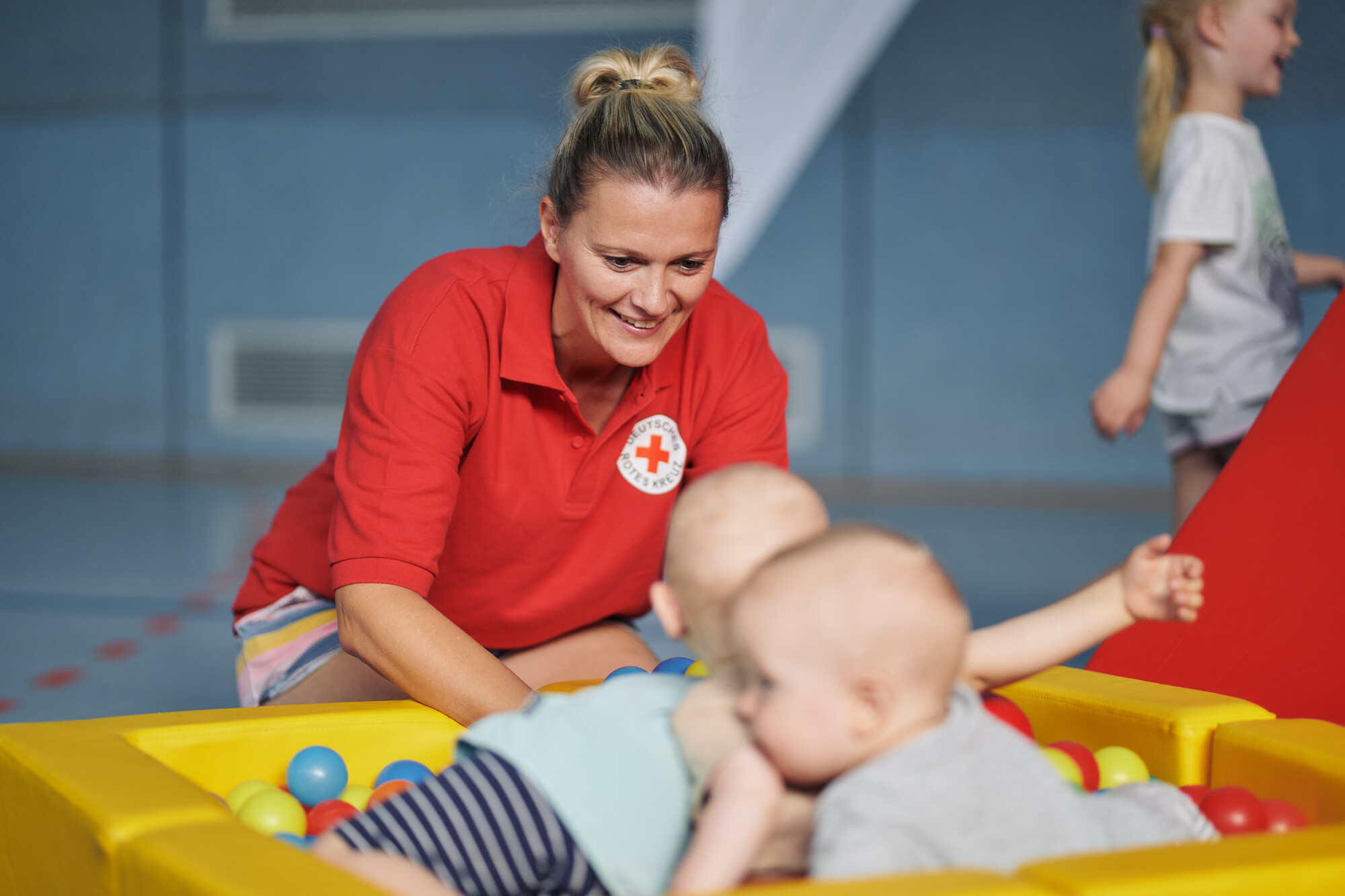 Babys im Bällebad, DRK-Mitarbeiterin betreut