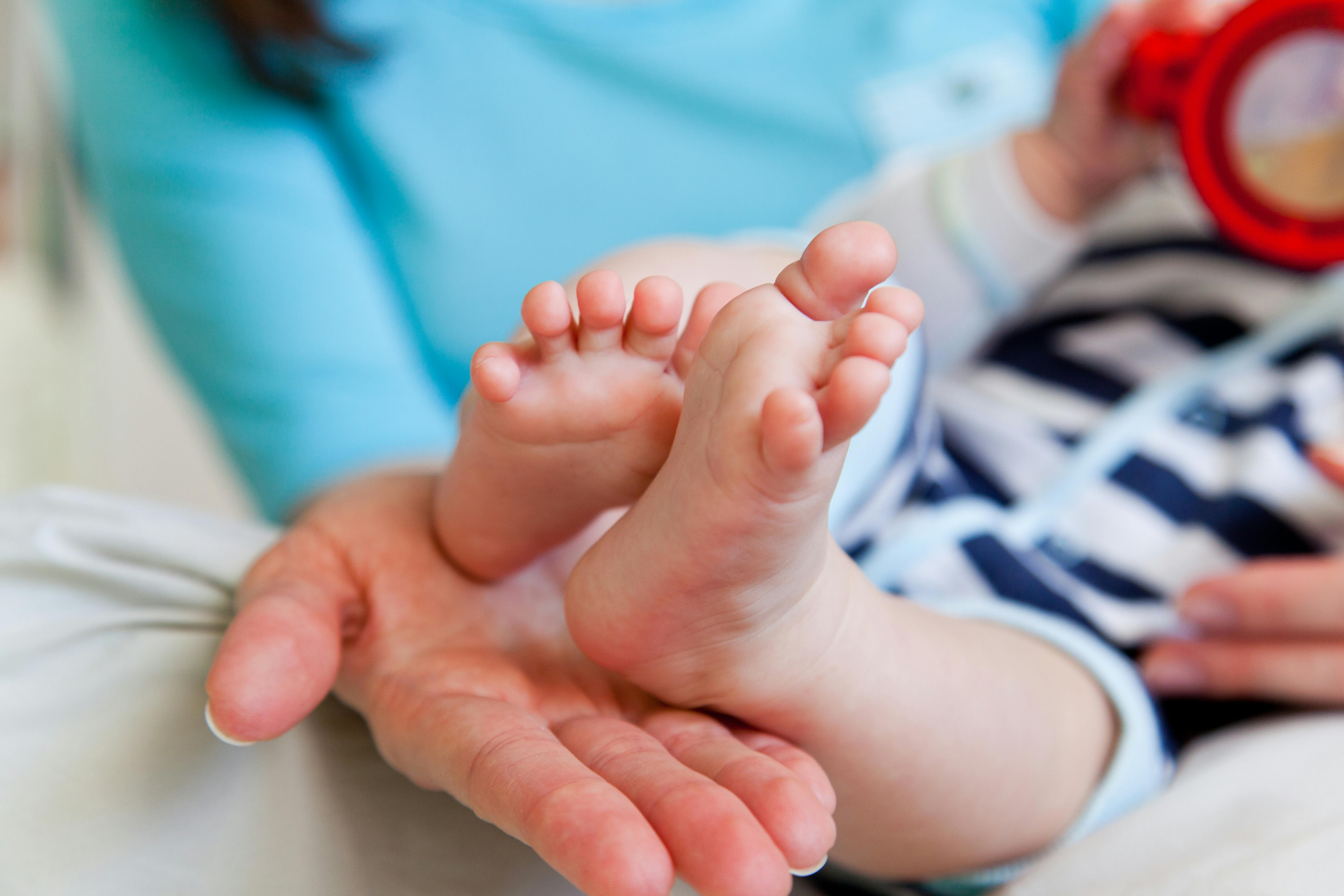 Eine Frauenhand hält Babyfüße