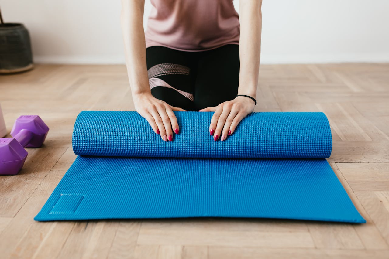 Junge Frau rollt blaue Gymnastikmatte zusammen