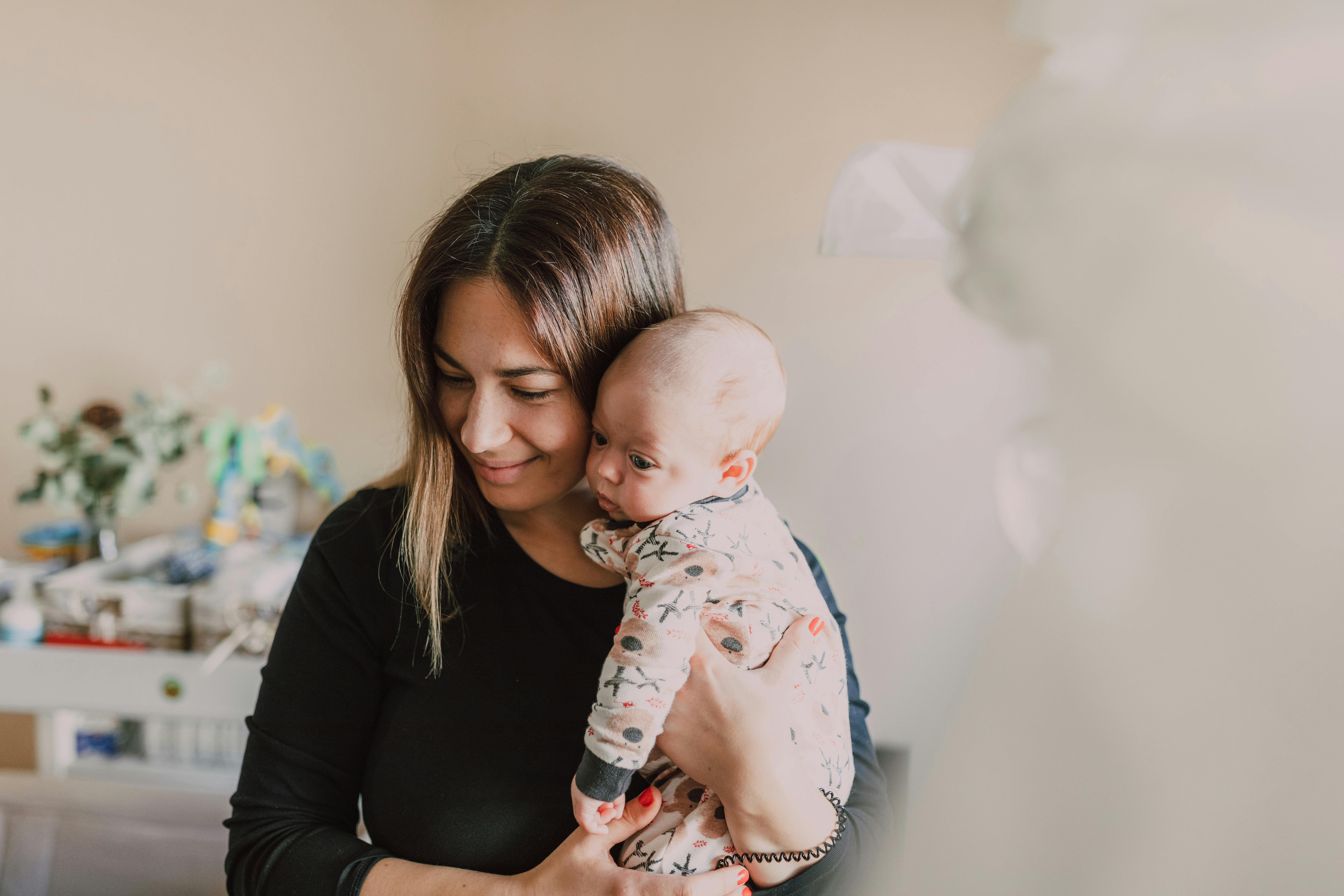 Junge Mutter lächelt mit Baby im Arm