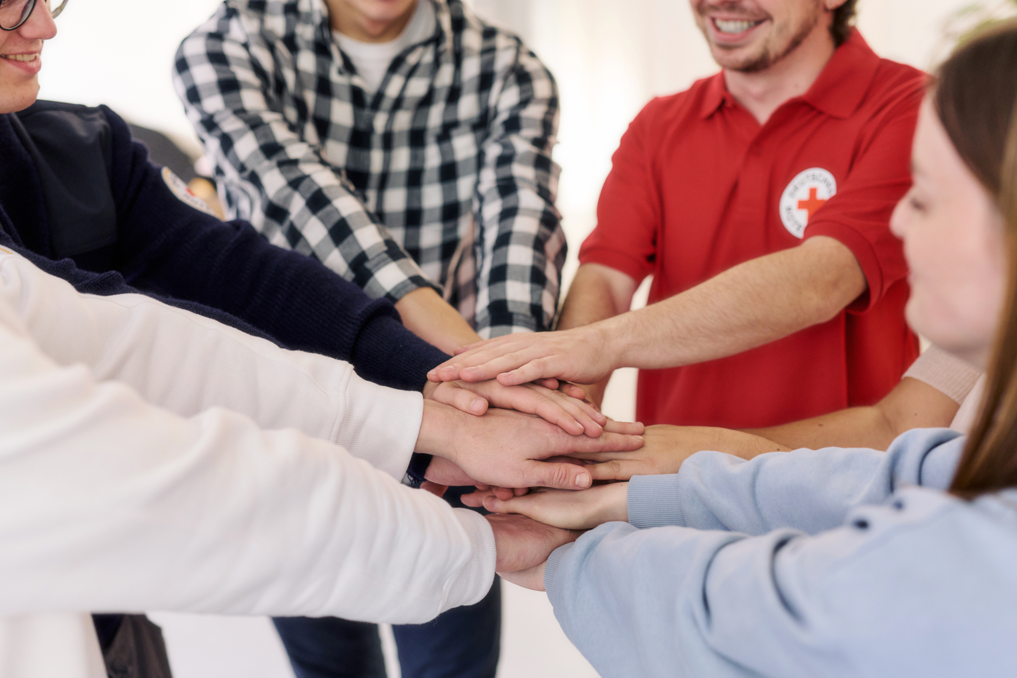 Symbolfoto Solidarität, Mitarbeitende vom DRK legen ihre Hände übereinander