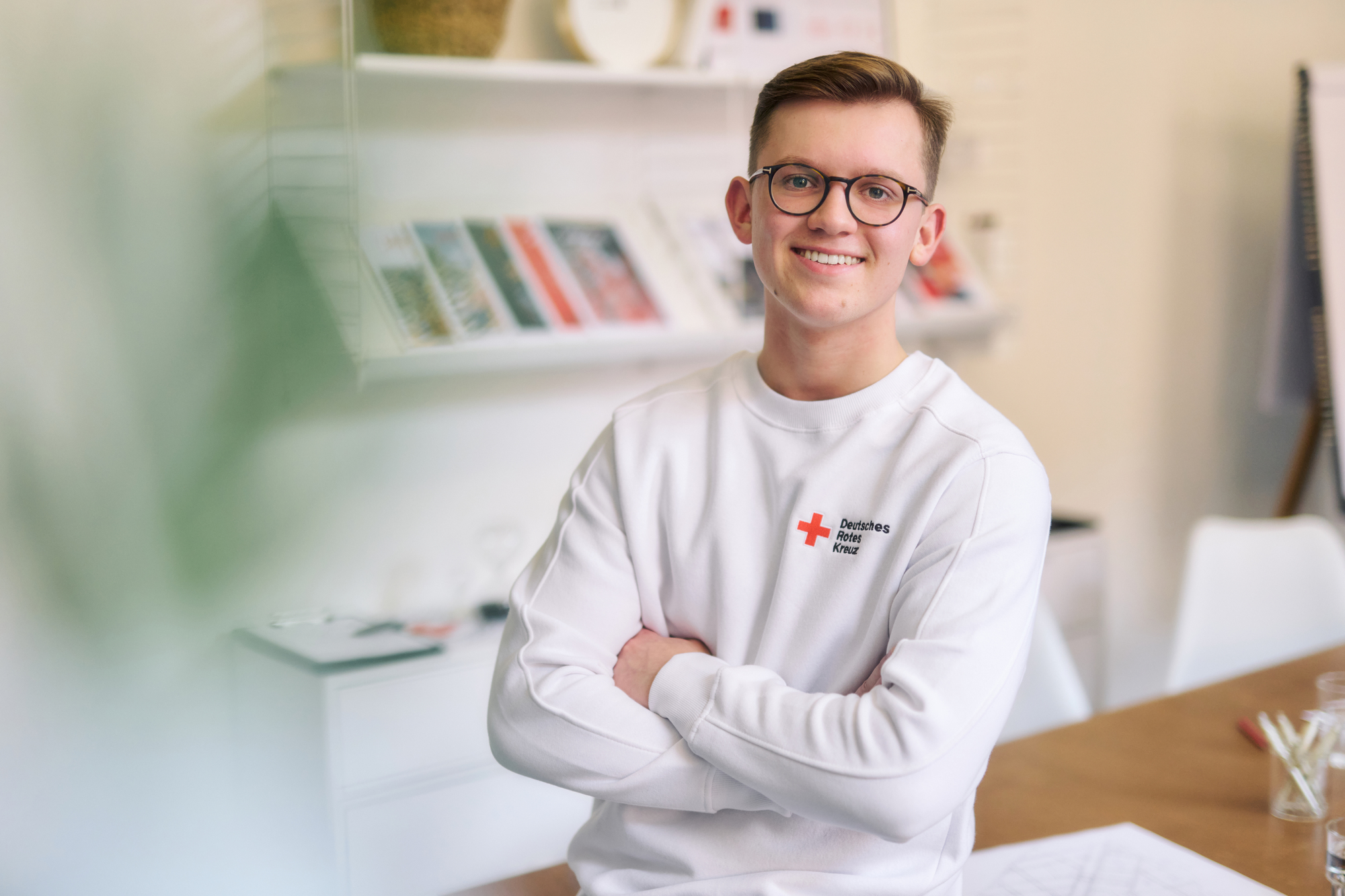 Symbolfoto junger Mitarbeiter des DRK, er trägt ein weißes Sweatshirt mit DRK - Logo