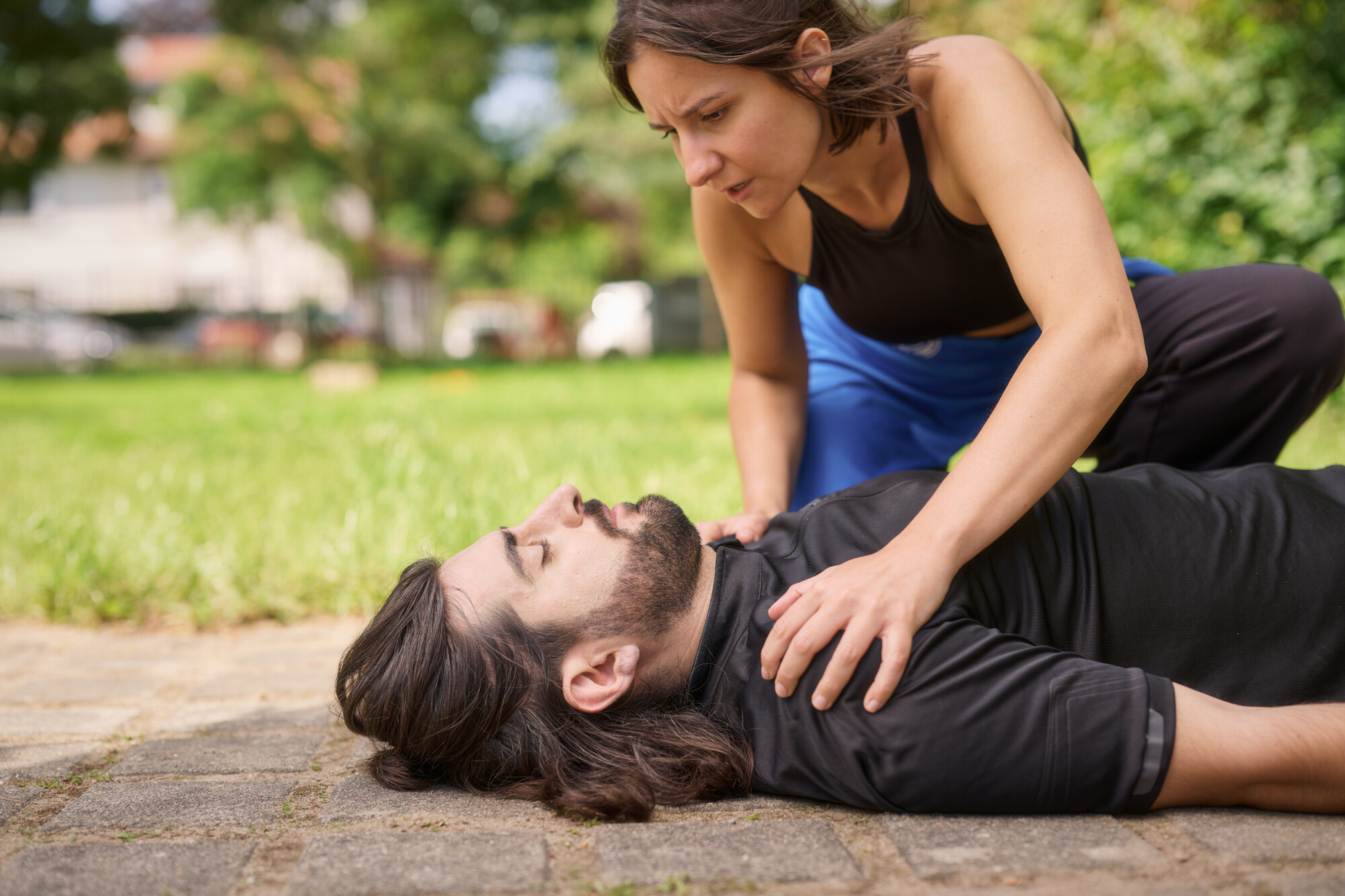 Erste Hilfe Situation. Der Mann ist beim Joggen zusammengebrochen. Die Frau reagiert auf den Notfall und überprüft das Bewusstsein des Mannes