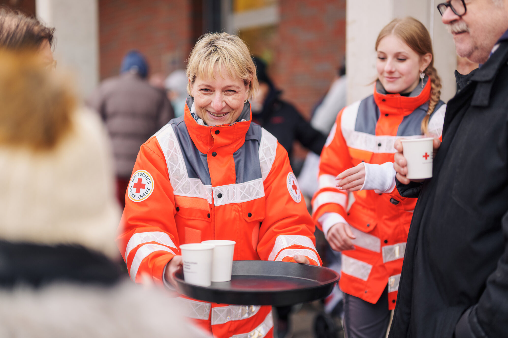 Ausgabe von heißem Kaffee in Pappbechern durch freiwillige Helferinnen