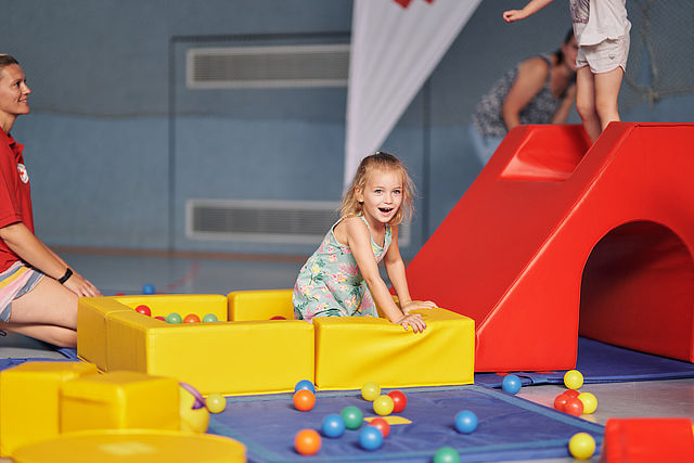 Kinder beim Sport, Mädchen in einem Bällebad in einer Turnhalle
