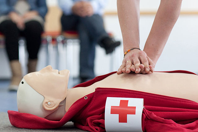 Eine Person macht eine Herz-Druck-Massage bei einer Reanimationspuppe des DRK