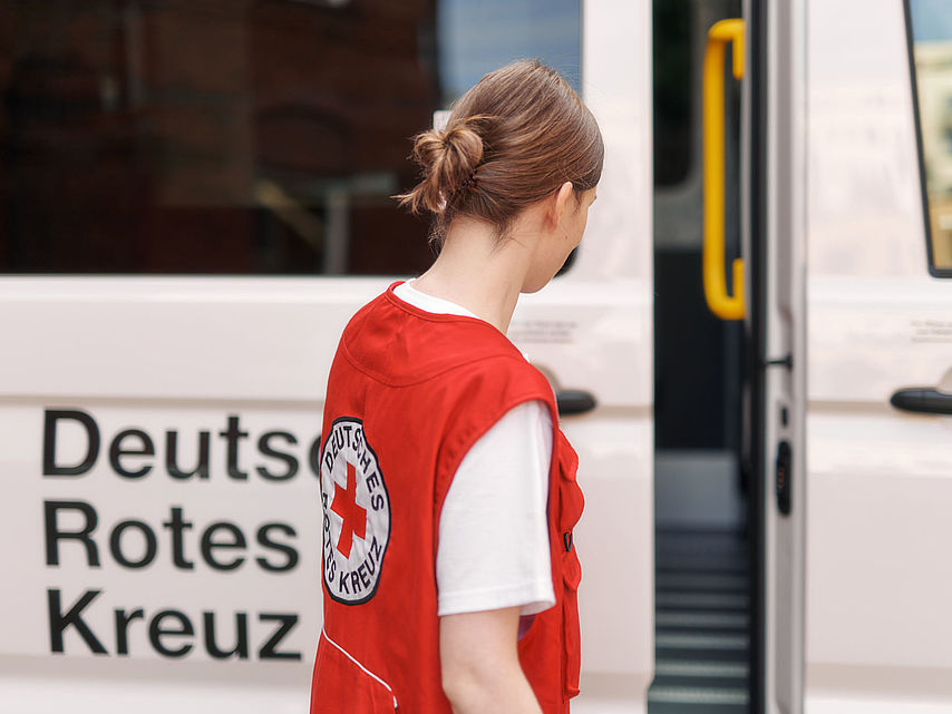 DRK-Helferin und Einsatzfahrzeug