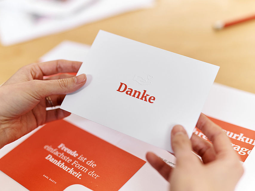 Symbolfoto Mappe mit Dokumenten des DRK (Dankesurkunde). Hände halten eine Karte mit einer Danksagung