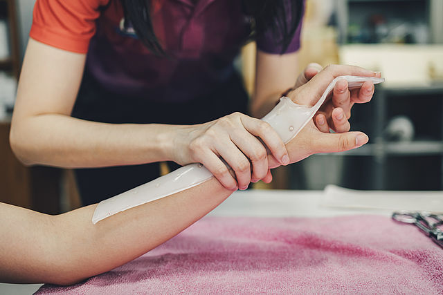 Therapeut, der ein Hilfsmittel zur Immobilisierung der Patientenhand herstellt. Schienenservice für die Rehabilitation von Handverletzungen der ergotherapeutischen Klinik.