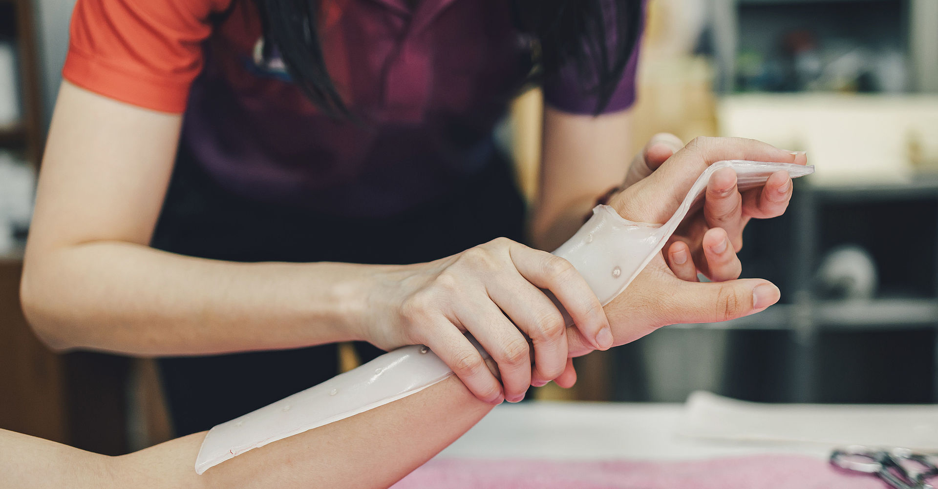 Therapeut, der ein Hilfsmittel zur Immobilisierung der Patientenhand herstellt. Schienenservice für die Rehabilitation von Handverletzungen der ergotherapeutischen Klinik.