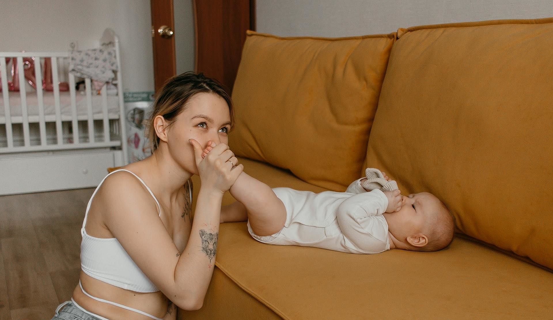 Junge Mutter küsst Fuß ihres Babys