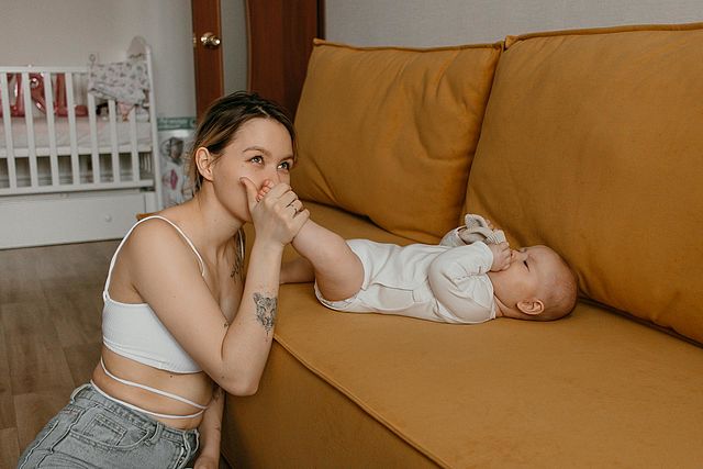 Junge Mutter küsst Fuß ihres Babys
