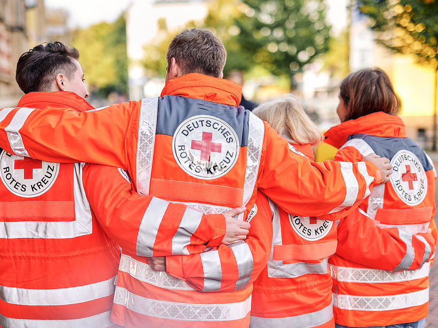 Symbolfoto, Team des DRK in Einsatzjacken, Ansicht von hinten