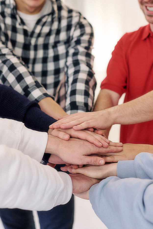 Symbolfoto Solidarität, Mitarbeitende vom DRK legen ihre Hände übereinander