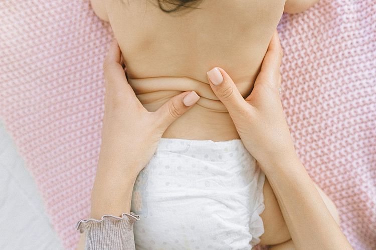 Baby wird in Bauchlage massiert