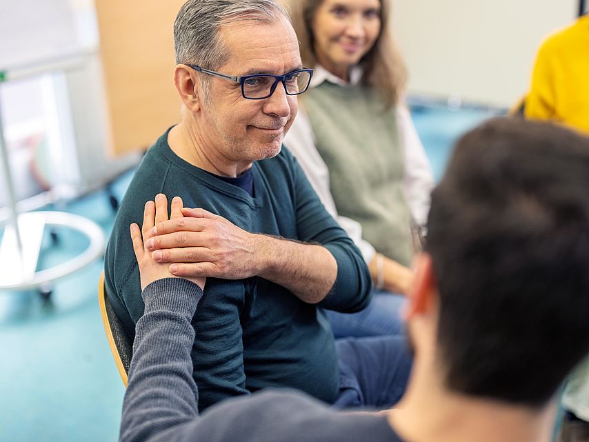 Älterer Mann bekommt emotionale Unterstützung während einer Gruppensitzung