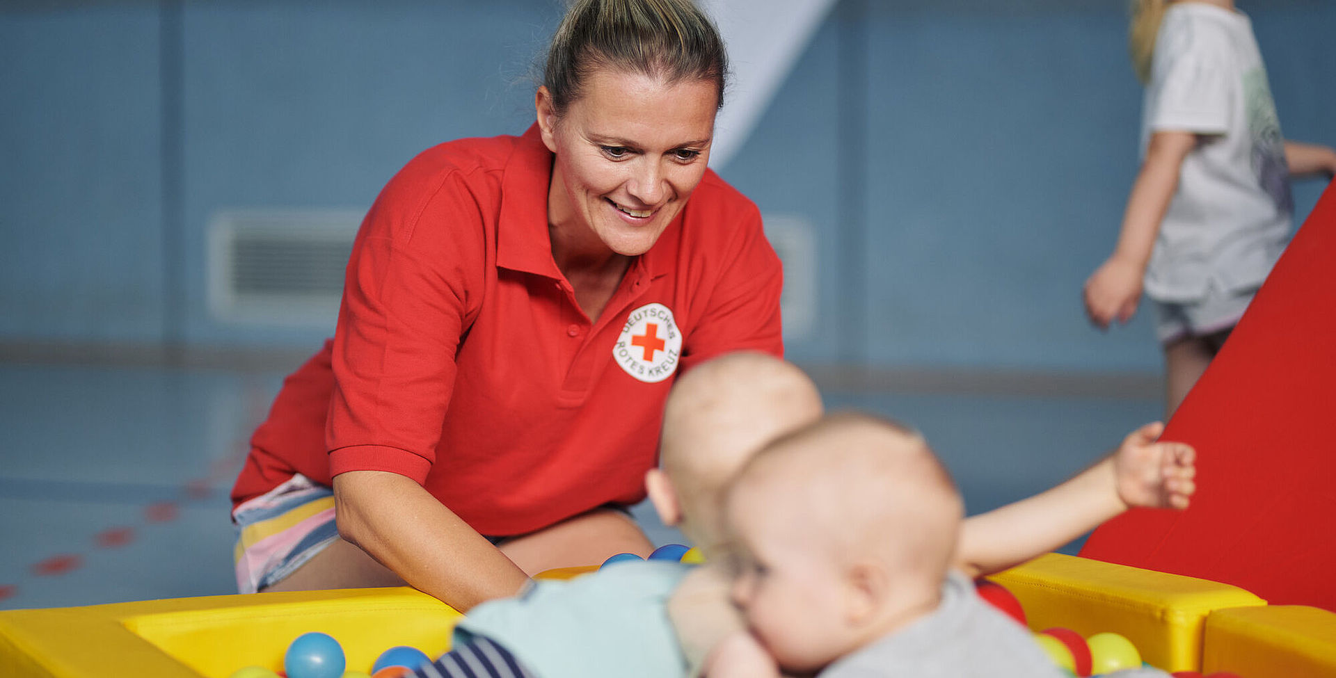 Babys im Bällebad, DRK-Mitarbeiterin betreut