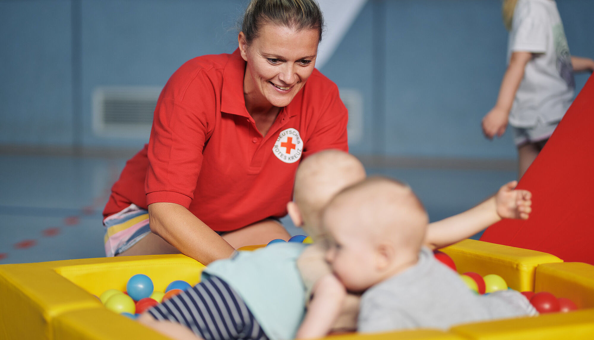 Babys im Bällebad, DRK-Mitarbeiterin betreut
