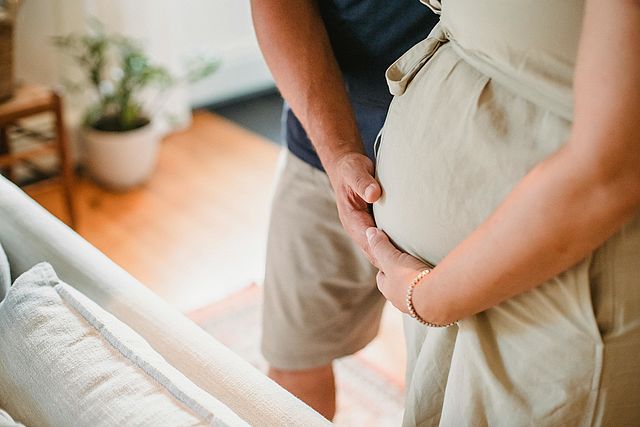 Frau mit Babybauch, Hände von Partner auf Bauch