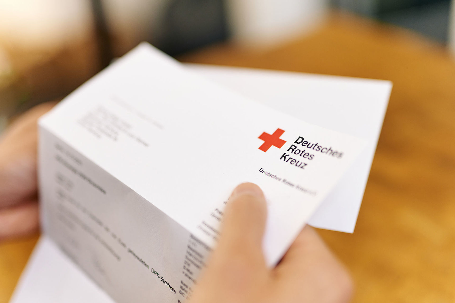 Symbolfoto Brief des DRK. Hand hält Briefbogen mit dem Logo
