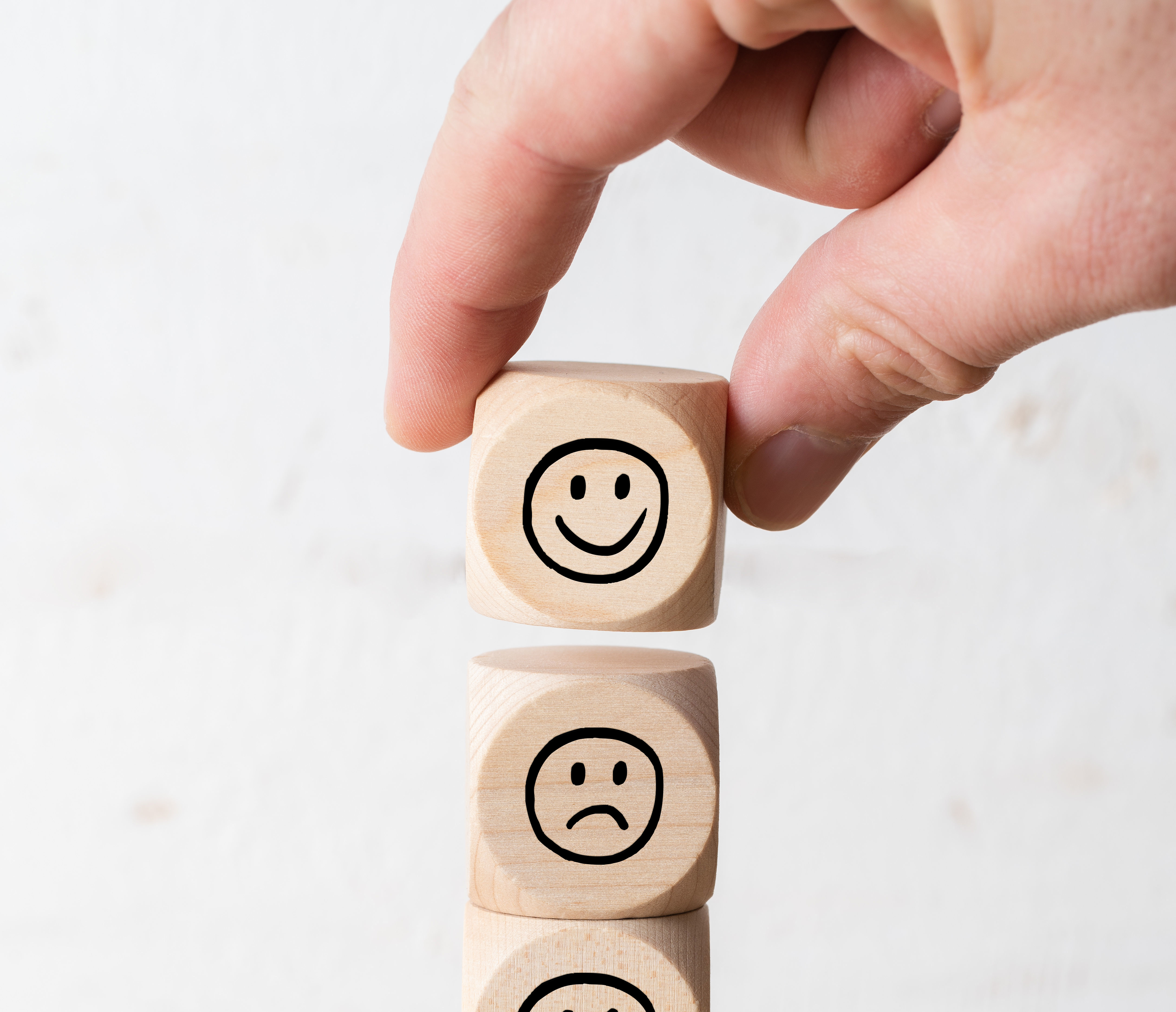 Übereinandergestapelte Würfel aus Holz mit traurigem und dann glücklichem Smiley