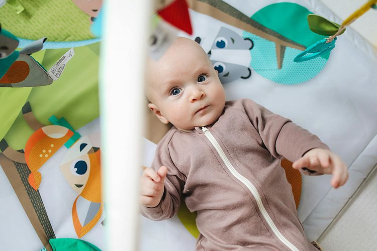 Baby liegt unter Spielbogen